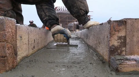 Builder aligns the horizontal level of the concrete with a trowel in foundation Stock Footage 57321969