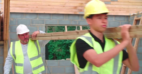 Builder And Apprentice Carrying Wood On Construction Site Stock Footage 56221729