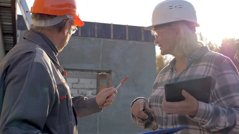Builder And Architect In Helmet Discuss Construction According To Plan Project Stock Footage 98699070