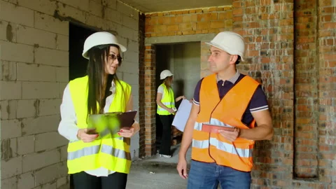 Builder and engineer inspect room of unfinished building Stock Footage 317612059