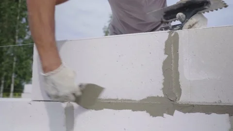 Builder applies adhesive composition or solution with spatula to wall structure. Stock Footage 158753319