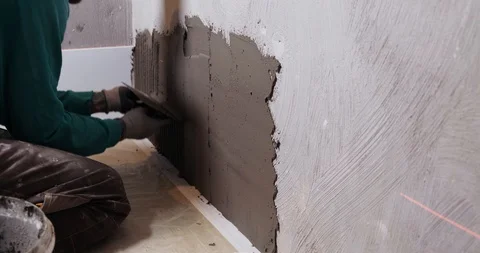 Builder applies cement composition to wall, prepares to adhere ceramic tiles Stock Footage 129839868