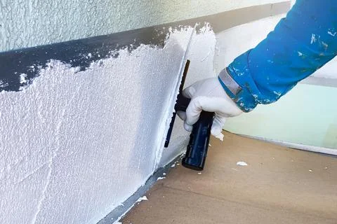The builder applies a fresh texture to the facade of the house. Large spatula Stock Photos