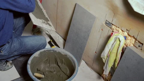 Builder applying adhesive to a large wall tile Stock Footage 142106106