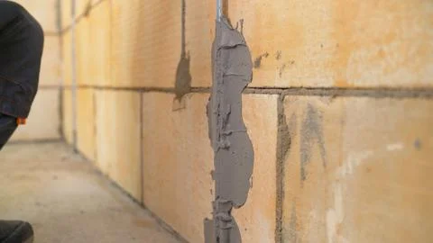 Builder applying fresh mortar to block wall during construction Stock Photos