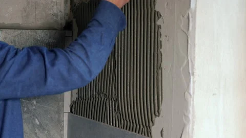 Builder applying fresh tile adhesive to a wall Video stock 142106023