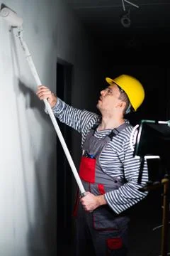 Builder applying paint on a wall with roll Stock Photos