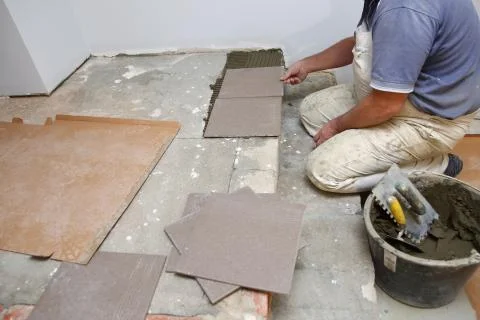  The builder arranges ceramic tiles on the stairs inside the building. Stock-Fotos