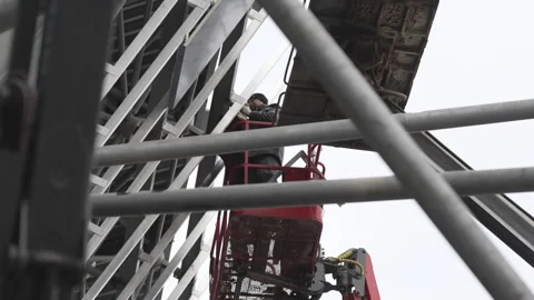 Builder assembles beam carcass standing in bucket of truck Stock Footage 314647975