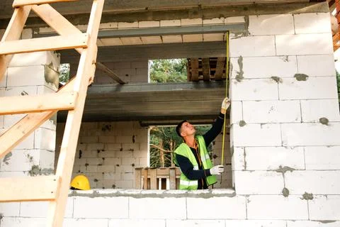 Builder assesses opening, measurement for windows or doors, brick wall layo.. Stock Photos
