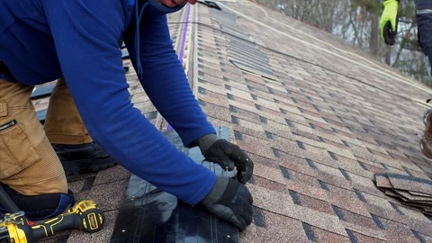 Builder attaches ridge on roof using a screw gun. Frame house under construction Stock Footage 127756813