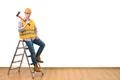 The builder with the ax standing on the ladder on the white wall background Photo