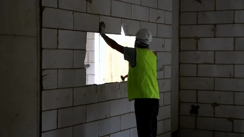 Builder with back to camera knocks breeze blocks out of a wall Stock Footage 112609254
