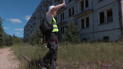 Builder with backpack and toolbox comes out of the building Stock Footage 77138504
