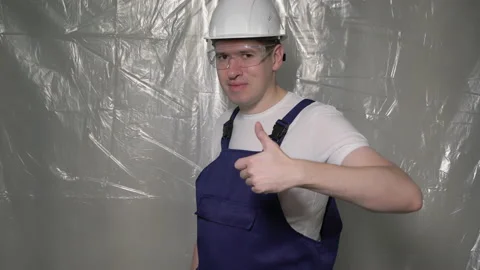 Builder in blue overalls and white hard hat helmet and protective glasses. 库存影片 170335588