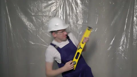 Builder in blue overalls and white hard hat. Funny playing like guitar, dancing. Vídeo Stock 170336007