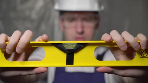 Builder in blue overalls and white hard hat helmet and glasses with level. Vidéo 170543014