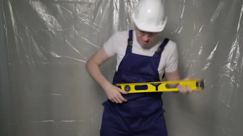 Builder in blue overalls and white hard hat. Funny playing like guitar, dancing. Vídeo Stock 171143464