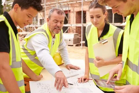 Builder On Building Site Discussing Work With Apprentice 스톡 사진