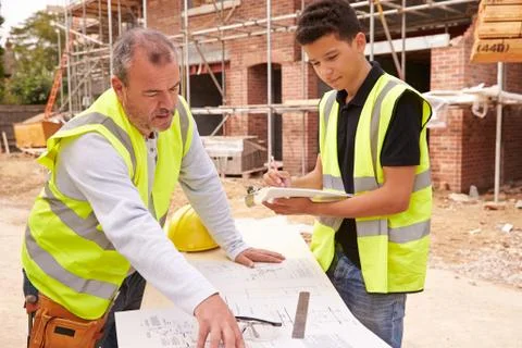 Builder On Building Site Discussing Work With Apprentice 库存照片