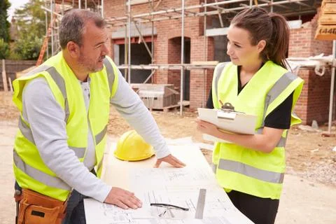 Builder On Building Site Discussing Work With Apprentice Stock Photos