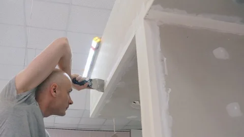 Builder carries out client order smoothing out puttied walls Stock Footage 124892492