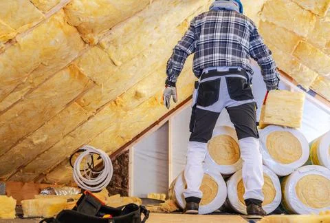 Builder carrying insulation inside an attic under renovation Stock Photos
