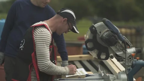 Builder checking project before cutting wooden boards with circular saw on farm Stock Footage 247518480
