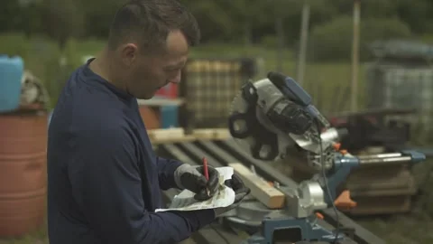 Builder checking project before cutting wooden boards with circular saw on farm Video stock 247523461