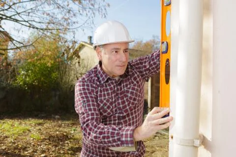 Builder checking the straightness of drainpipe Stock Photos