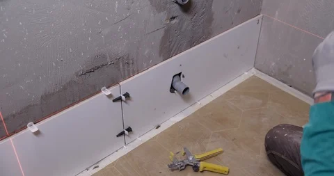 Builder checks correct laying of ceramic tiles in bathroom with large level Stock Footage 129839697