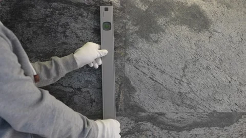 The builder checks the vertical and horizontal planes with a tool. Stock Footage 258470947