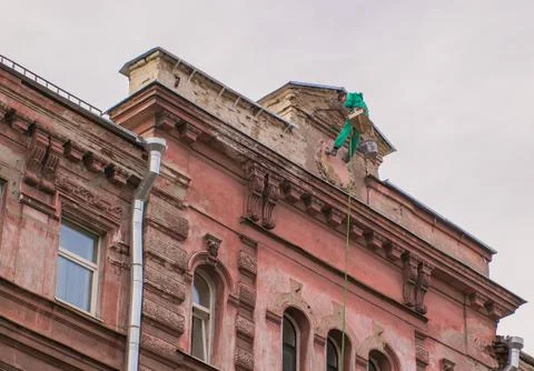 Builder-climber hanging on the top of the facade a building talking cell phon Stock Photos