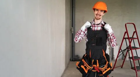 Builder at construction site celebrating victory and winning standing against Stock Photos