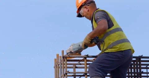 A builder at a construction site with the help of a grinder cuts off the fitting Stock Footage 147635455