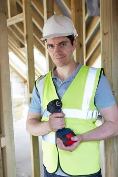 Builder on construction site holding cordless drill Stock Photos