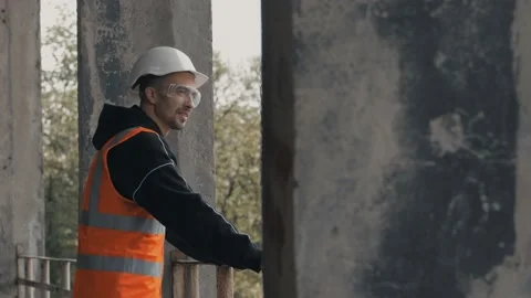 A Builder on a construction site leaning on the railing looks into the distance Stock Footage 131446182