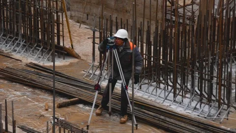 A builder at a construction site looks at a rangefinder Concrete foundation on Stock Footage 277078835
