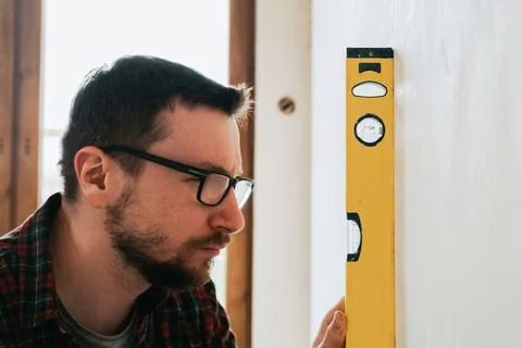 Builder at construction site measuring plumb with focus on spirit level Stock Photos