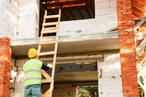 Builder at construction site, worker climbs ladder, assembling scaffolding,.. Stock Photos