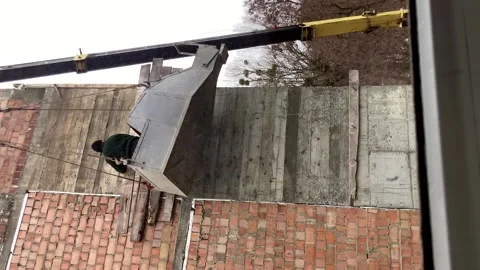 A builder in a container for supplying concrete mortar, violating safety Stock Footage 263237760