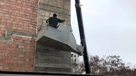 A builder in a container for supplying concrete solution, violating safety Stock Footage 263497381