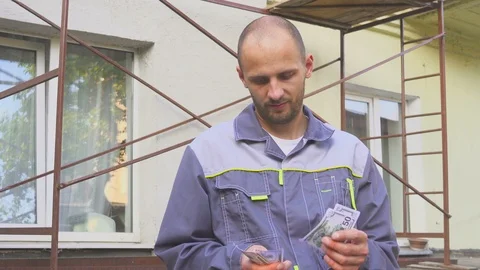 Builder counting his salary standing at the construction site Stock Footage 124704132