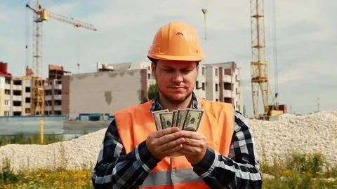 The builder counts the money against the background of the construction site and Stock Footage 129056701