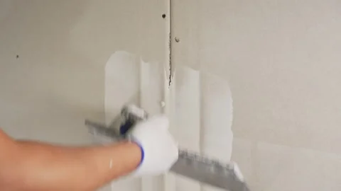 The builder covers the joint of two sheets of drywall with a spatula with putty Vídeos de archivo 212833290