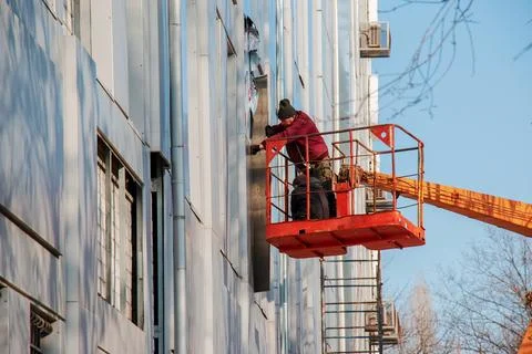 Builder in a crane basket repairs the coating of a metal structure on the w.. Stock Photos