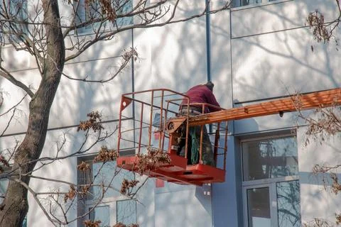 Builder in a crane basket repairs the coating of a metal structure on the w.. Stock Photos