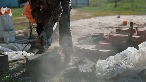 The builder cuts a claydite-concrete block with a manual cut-off machine. Stock Footage 79877037