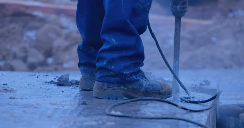 A builder cuts a hole in a concrete slab with a large industrial rock drill Stock Footage 147612986