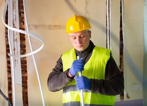 Builder cuts plastic pipe with special interior in house under construction Stock Photos